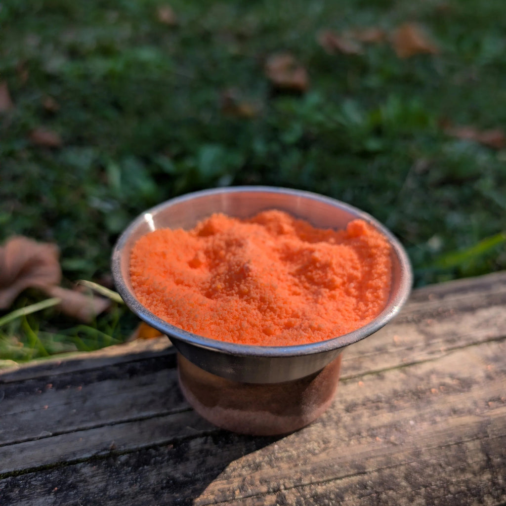 Bowl of Phoenix Ash orange fizzy powder on a log