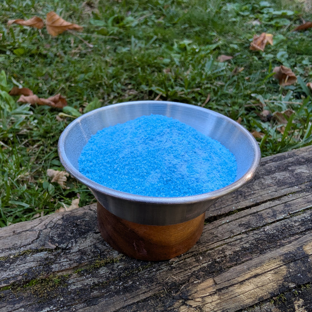 Bowl of Poseidon's Spell blue fizzy powder on a log