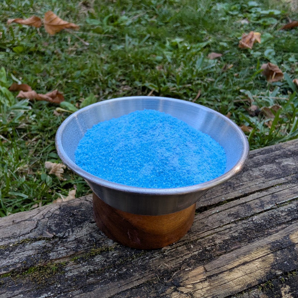 Bowl of Poseidon's Spell blue fizzy powder on a log