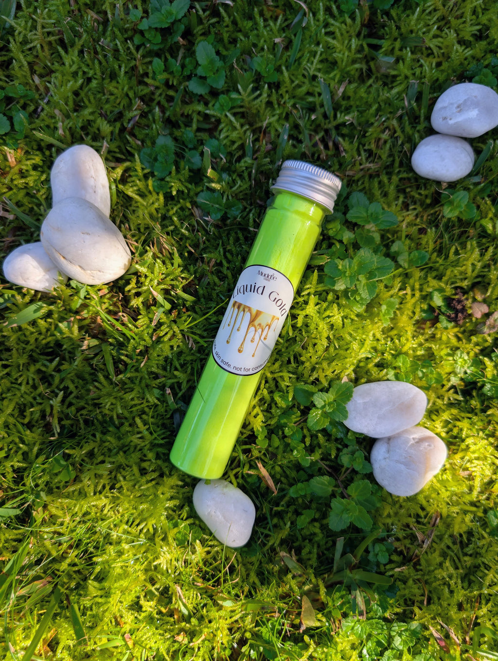 Standard test tube of lime green fizzy powder on grass among white stones
