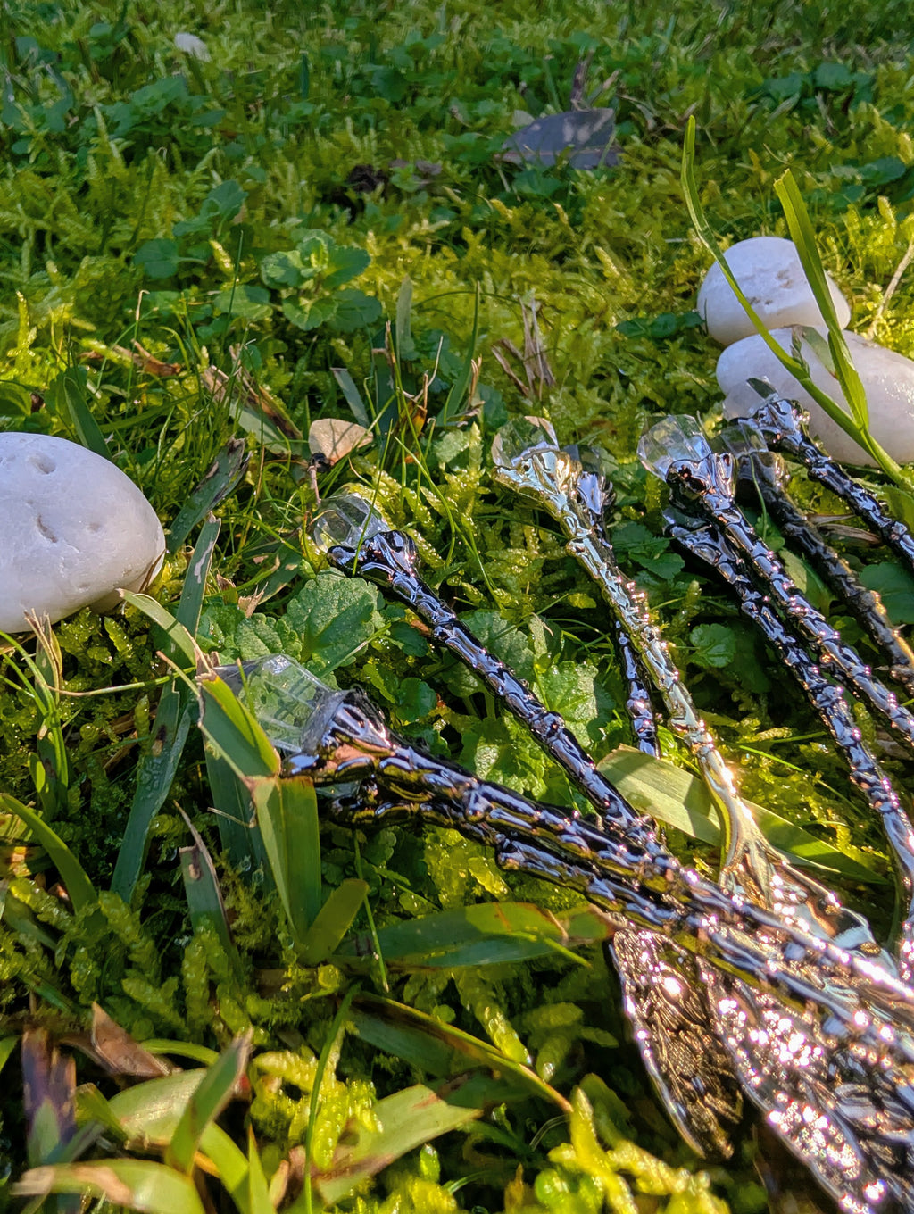Silver crystal teaspoons laid on grass beside a white stone