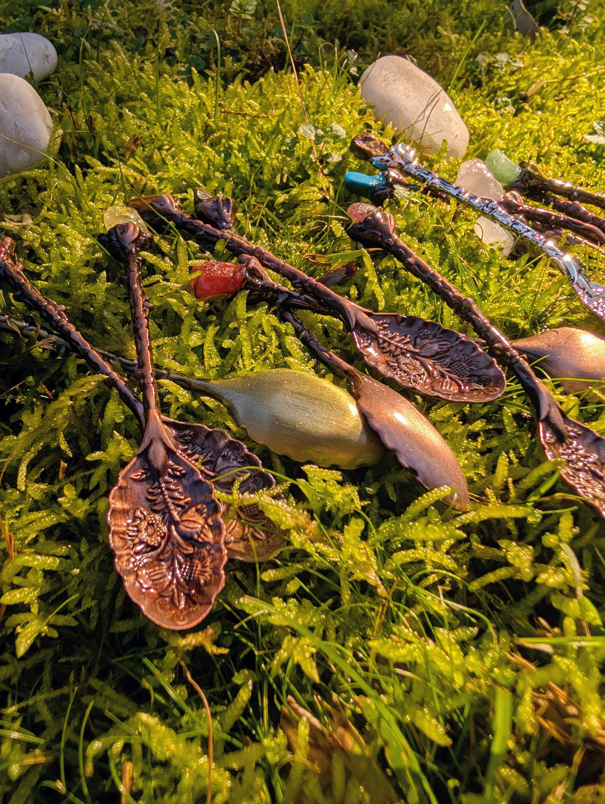 Bronze gemstone spoons with leaf-shaped bowls laid on grass 
