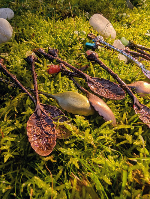 Bronze gemstone spoons with leaf-shaped bowls laid on grass 