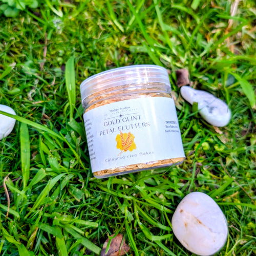 Copper Glint Petal Flutters jar with an orange label on grass beside white stones