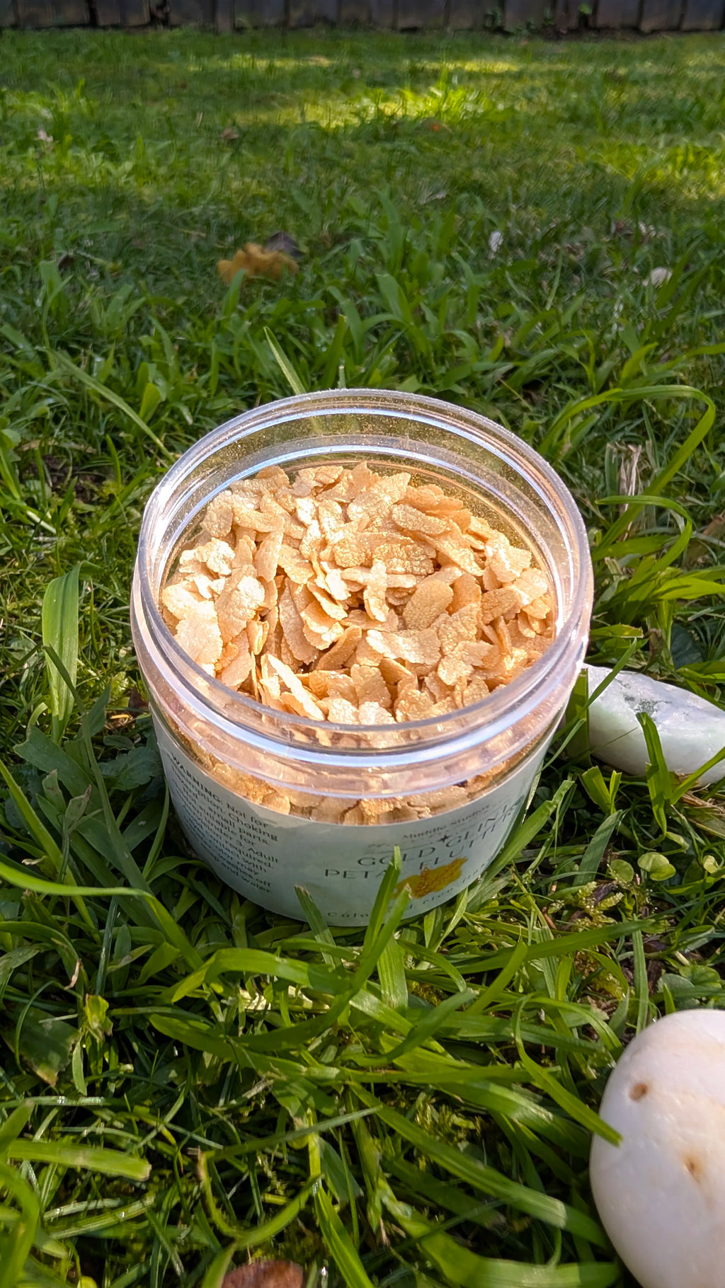 Open jar of Gold Glint Petal Flutters, golden rice flakes, close up 