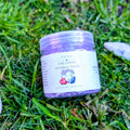 Amethyst Sparkle Dust jar filled with purple crystals, on grass beside white stones