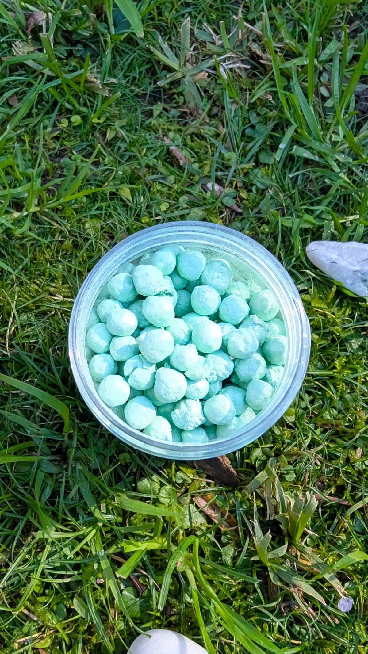 Open jar of Mint Dawn Pearls, mint green tapioca pearls, seen from above on grass