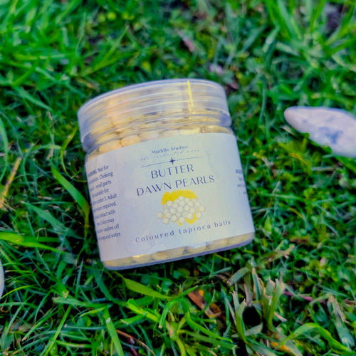 Butter Dawn Pearls jar with a pale yellow label on grass beside white stones