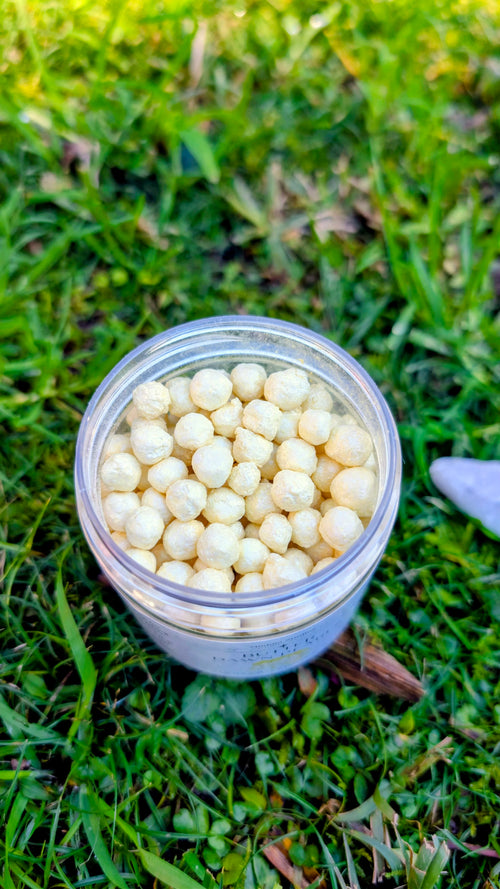 Open jar of Butter Dawn Pearls, cream tapioca pearls, seen from above on grass