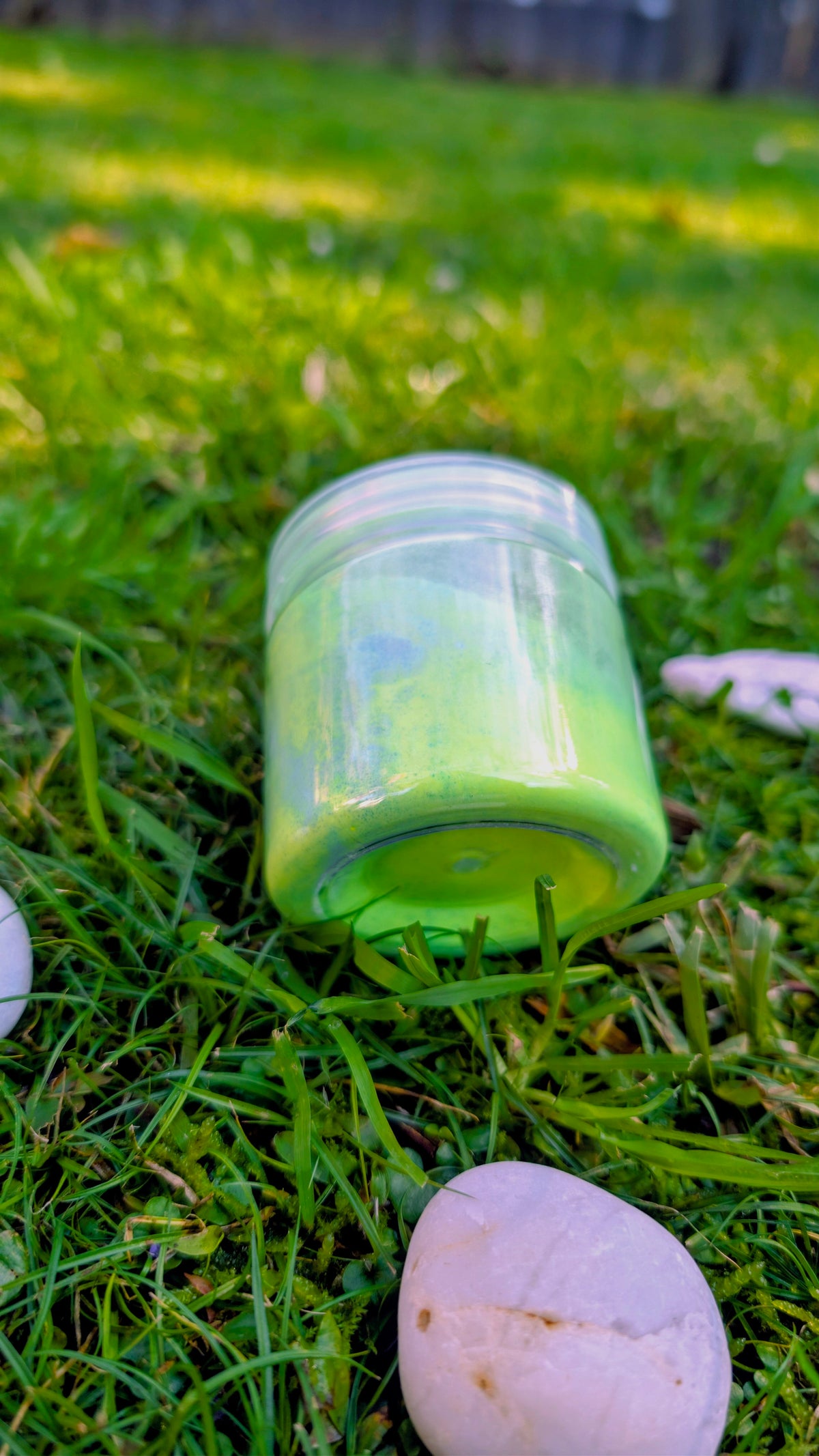 Citrus Wave fizzy powder jar with bright green powder, on grass