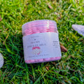 Blush Dawn Pearls jar with a pink label on grass beside white stones