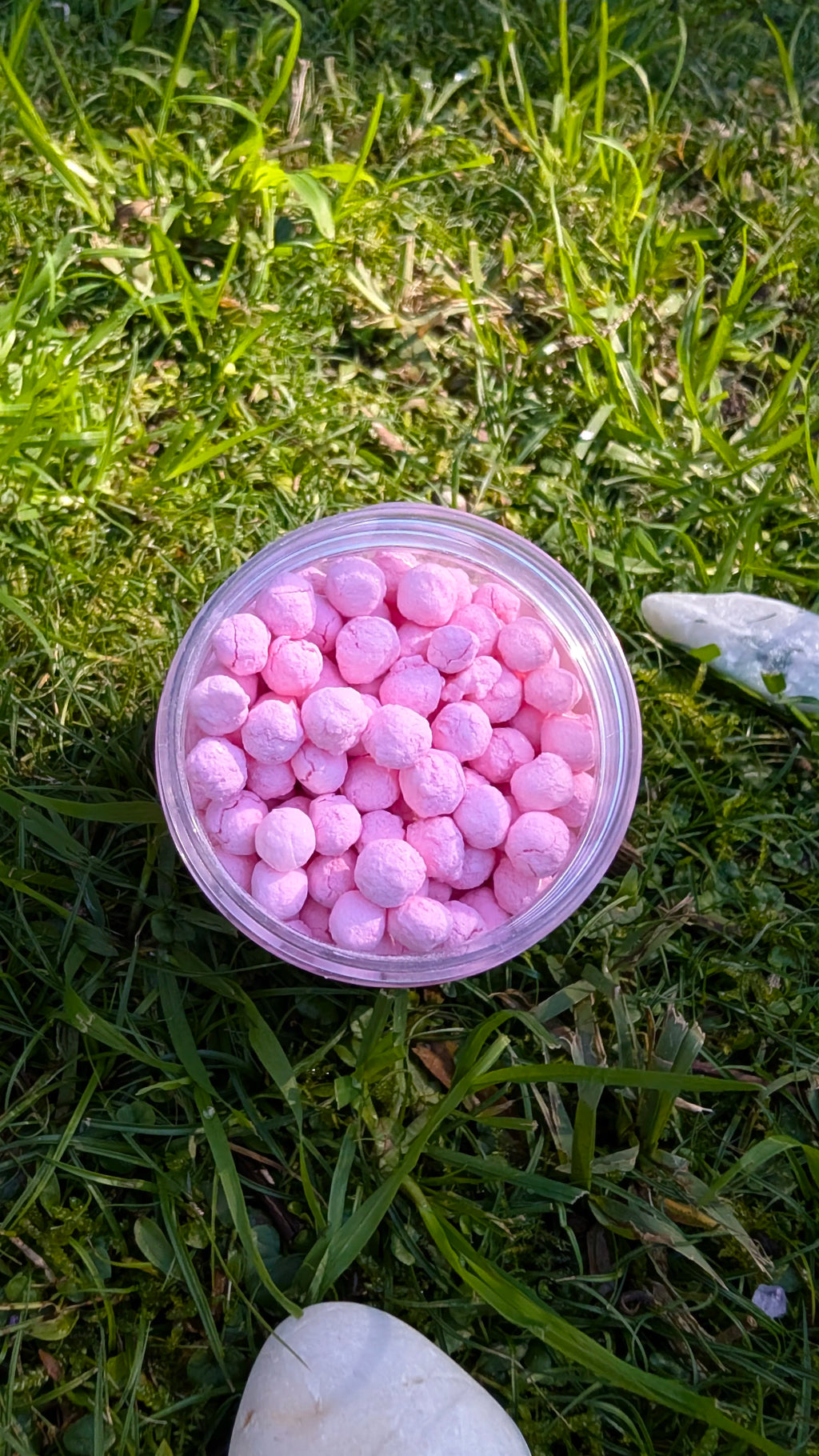 Open jar of Blush Dawn Pearls, pink tapioca pearls, seen from above on grass 