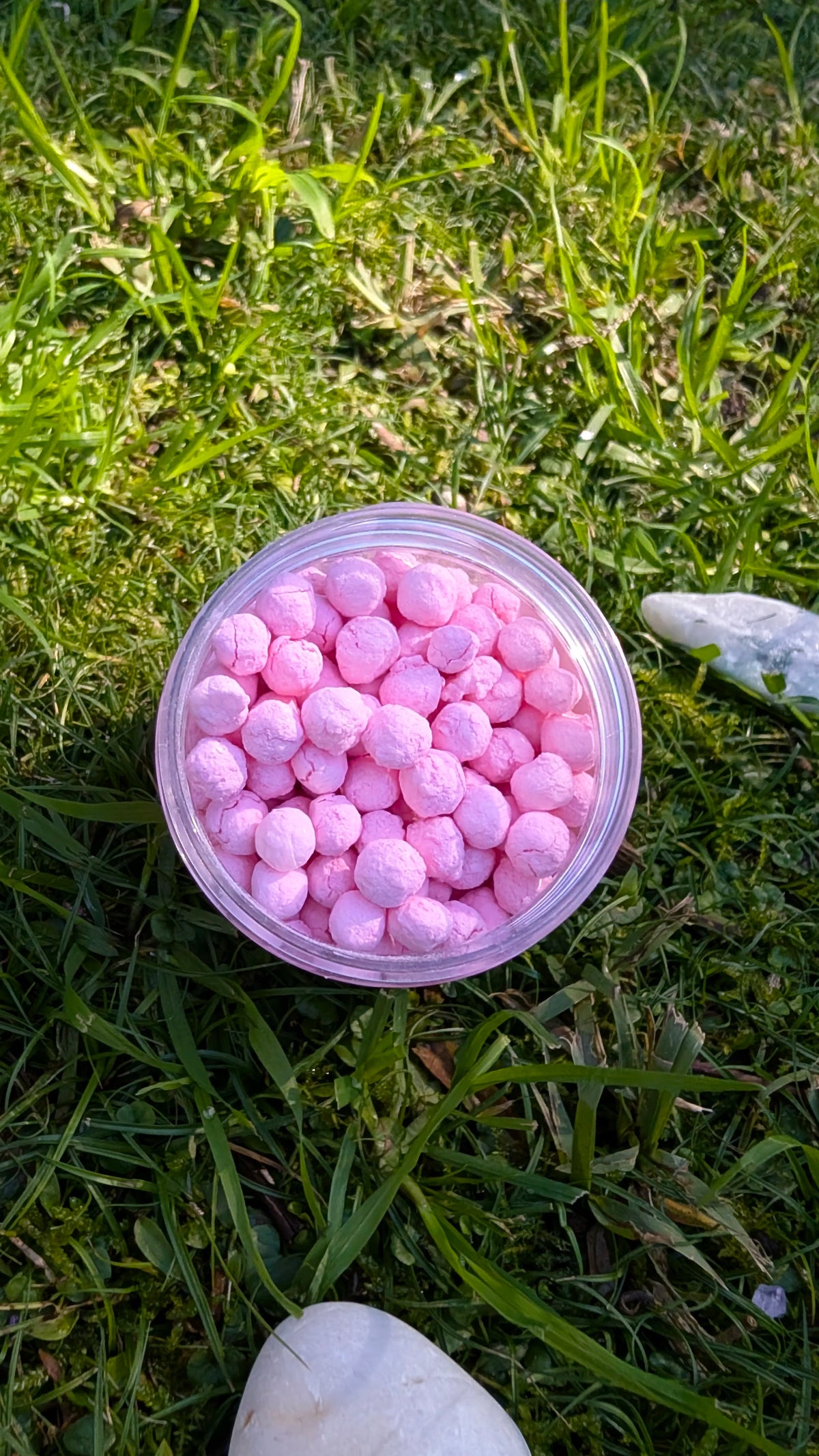 Open jar of Blush Dawn Pearls, pink tapioca pearls, seen from above on grass 