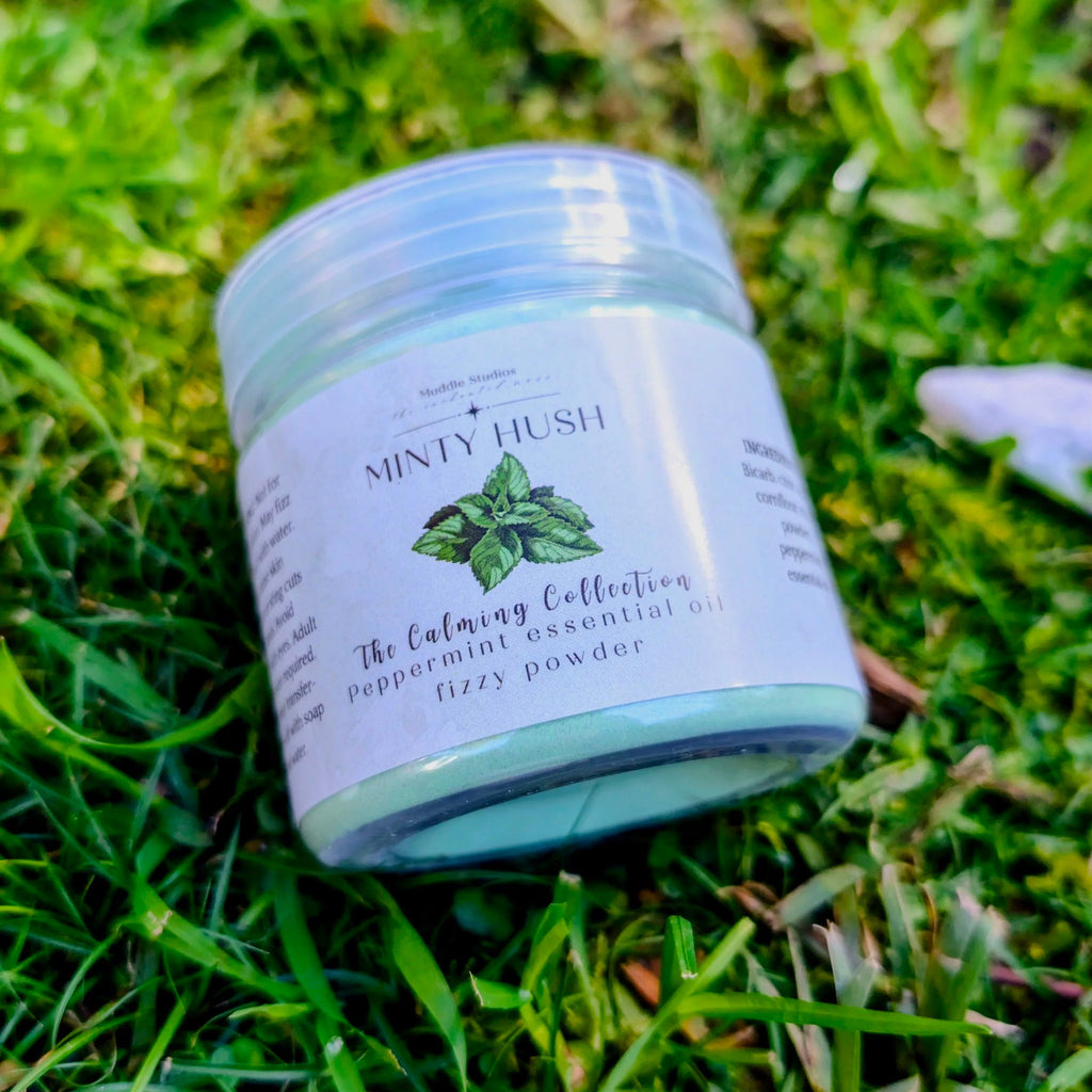 Minty Hush fizzy powder jar with a peppermint leaf label, close up on grass