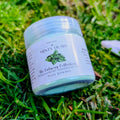 Minty Hush fizzy powder jar with a peppermint leaf label, close up on grass