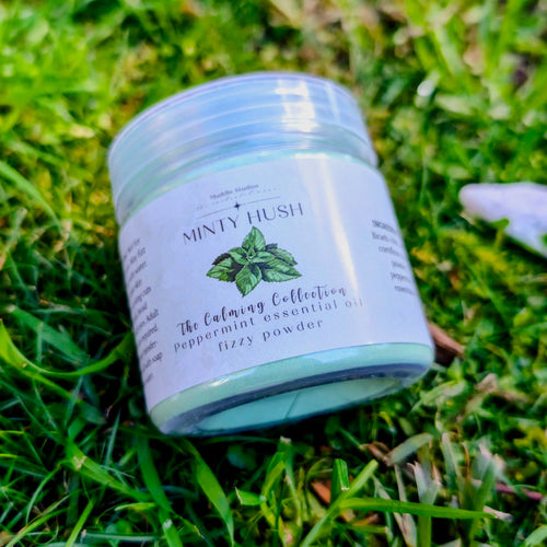 Minty Hush fizzy powder jar with a peppermint leaf label, close up on grass