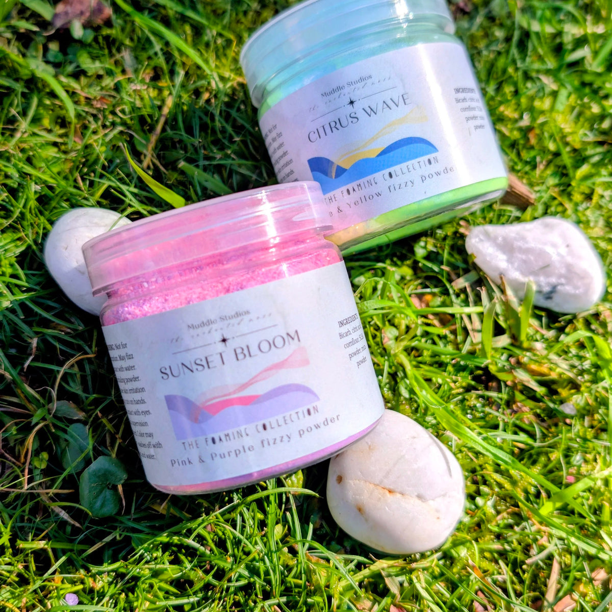Citrus Wave and Sunset Bloom fizzy powder jars side by side on grass