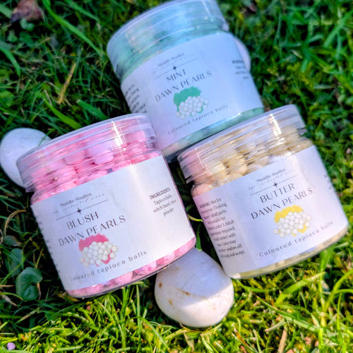 Mint, Blush and Butter Dawn Pearls jars grouped together on grass with a white stone
