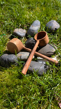 Small wooden pot and scoop on grass among dark stones