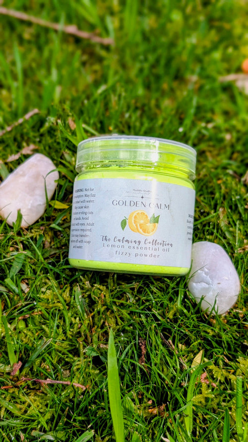 Golden Calm lemon fizzy powder in a 150ml jar with a lemon label, on grass beside two white stones